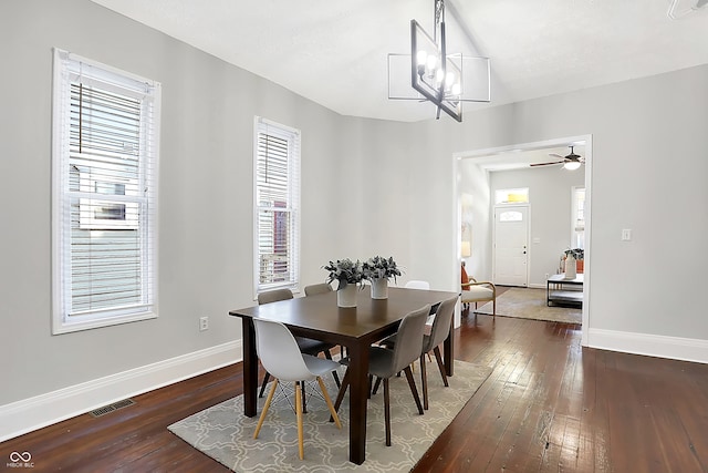 dining room with ceiling fan with notable chandelier, a healthy amount of sunlight, and dark hardwood / wood-style flooring