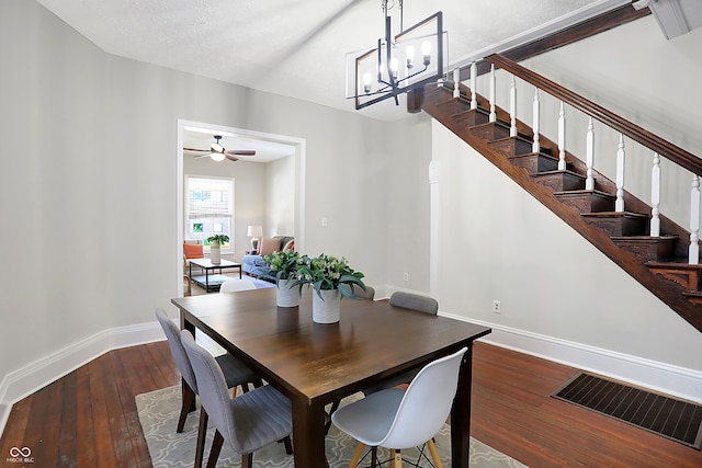 dining area with dark wood-type flooring, a textured ceiling, and ceiling fan with notable chandelier