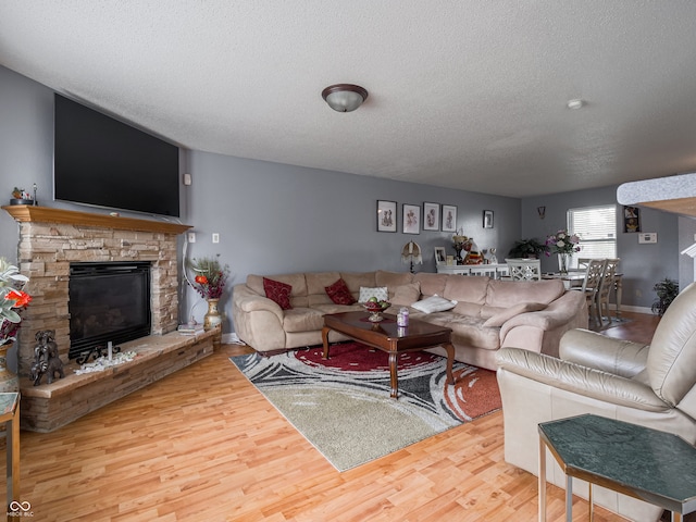 living room featuring a textured ceiling, hardwood / wood-style flooring, and a fireplace