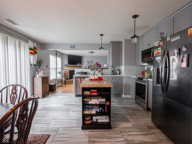 kitchen featuring a fireplace, stainless steel appliances, backsplash, gray cabinets, and a textured ceiling