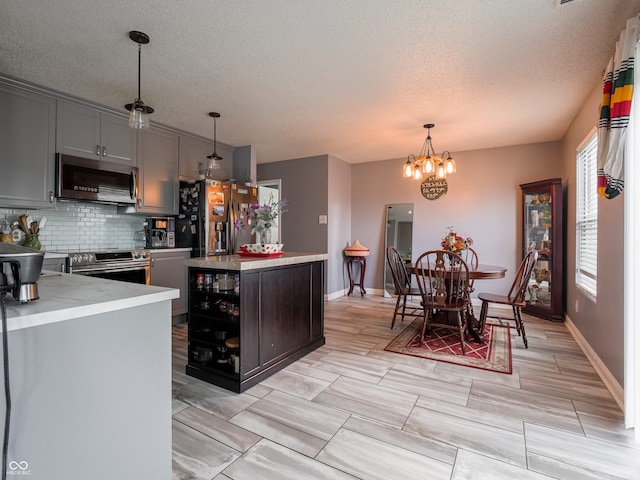 kitchen with stainless steel appliances, a center island, pendant lighting, and gray cabinets