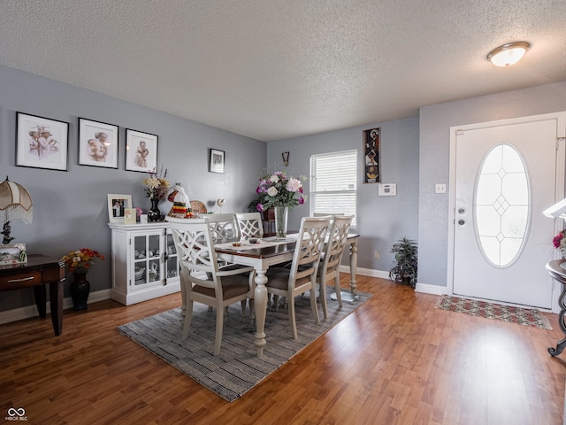 dining space with hardwood / wood-style flooring and a textured ceiling