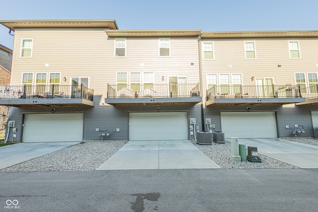 back of house with central air condition unit, a garage, and a balcony