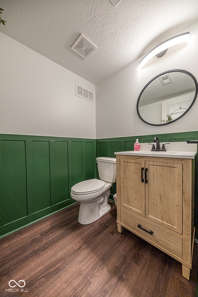 bathroom with toilet, hardwood / wood-style floors, vanity, and a textured ceiling