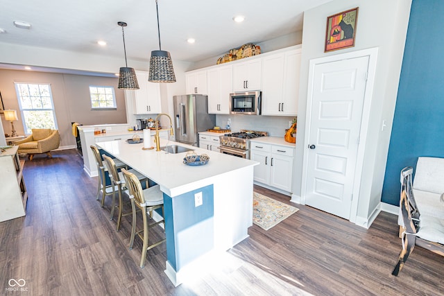 kitchen with sink, a breakfast bar, pendant lighting, premium appliances, and white cabinets