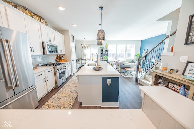 kitchen with a kitchen island with sink, high end appliances, sink, white cabinets, and dark hardwood / wood-style flooring