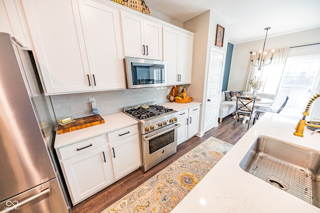 kitchen with dark hardwood / wood-style flooring, appliances with stainless steel finishes, white cabinetry, pendant lighting, and sink