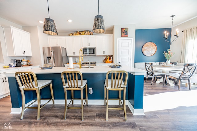 kitchen with dark hardwood / wood-style floors, appliances with stainless steel finishes, a kitchen island with sink, and white cabinets