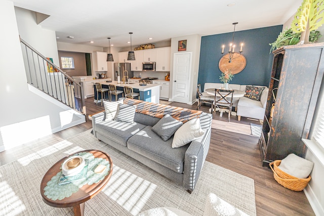 living room featuring sink, a notable chandelier, and light hardwood / wood-style floors