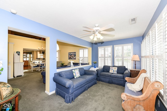 living room with a textured ceiling, carpet floors, and ceiling fan with notable chandelier