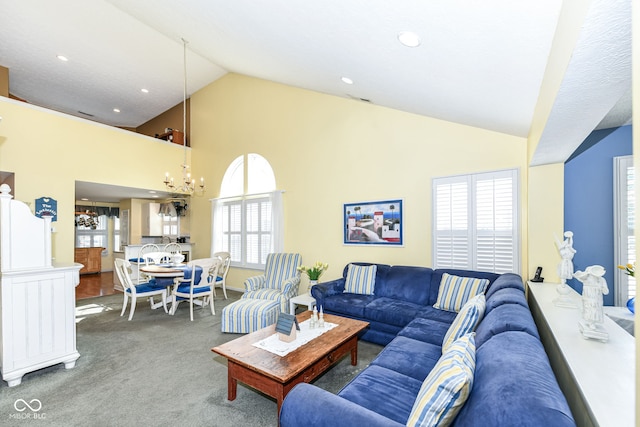 living room with high vaulted ceiling, carpet, a wealth of natural light, and an inviting chandelier