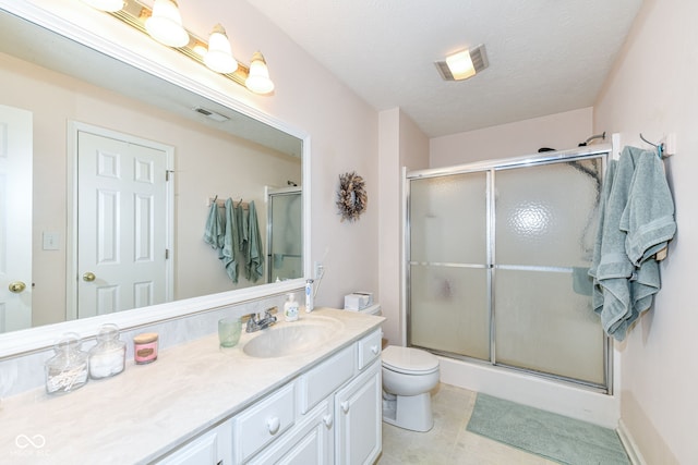 bathroom with a textured ceiling, toilet, tile patterned floors, walk in shower, and vanity