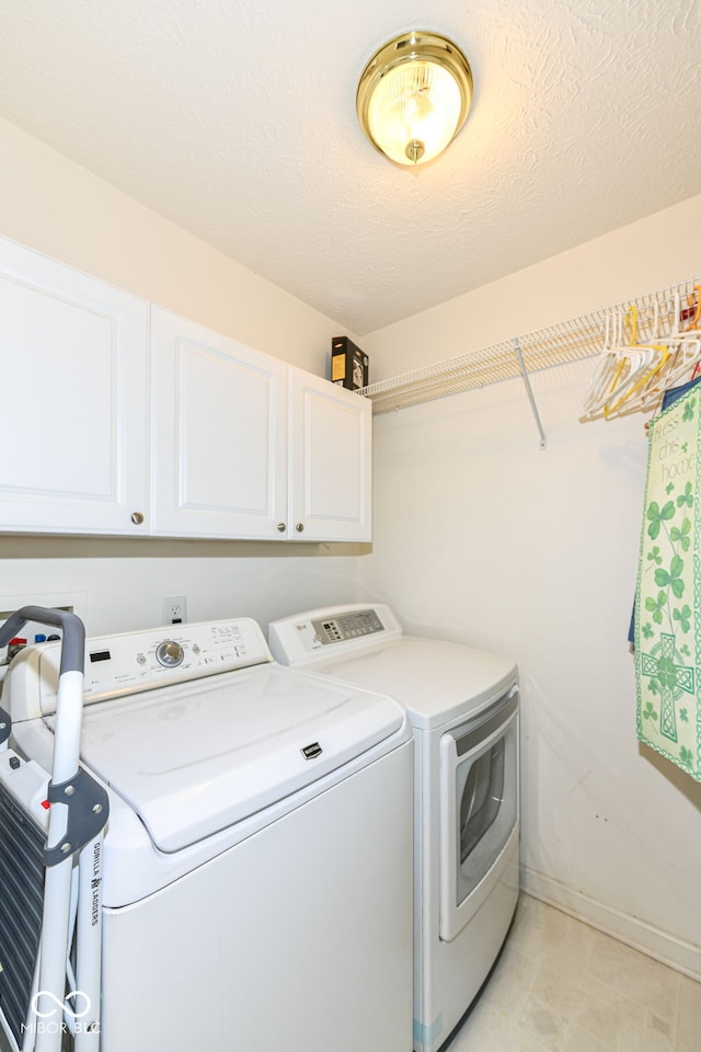 laundry room with cabinets, a textured ceiling, and washing machine and clothes dryer