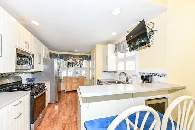 kitchen with sink, kitchen peninsula, stainless steel appliances, and plenty of natural light