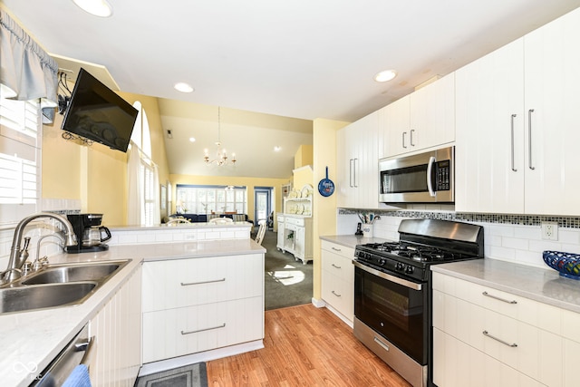 kitchen featuring kitchen peninsula, lofted ceiling, appliances with stainless steel finishes, pendant lighting, and sink