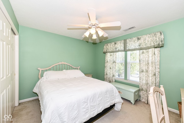 bedroom featuring light colored carpet, a closet, and ceiling fan