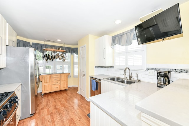 kitchen featuring hanging light fixtures, sink, white cabinetry, appliances with stainless steel finishes, and light hardwood / wood-style floors