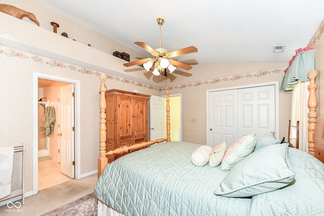 bedroom featuring a closet, ceiling fan, vaulted ceiling, connected bathroom, and light colored carpet