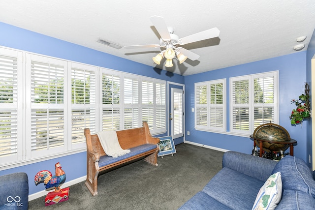 living area featuring ceiling fan, a textured ceiling, and dark colored carpet