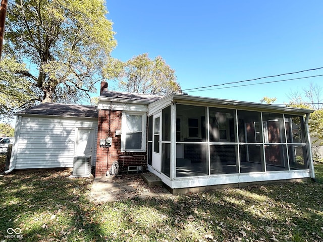 rear view of house with central air condition unit and a sunroom