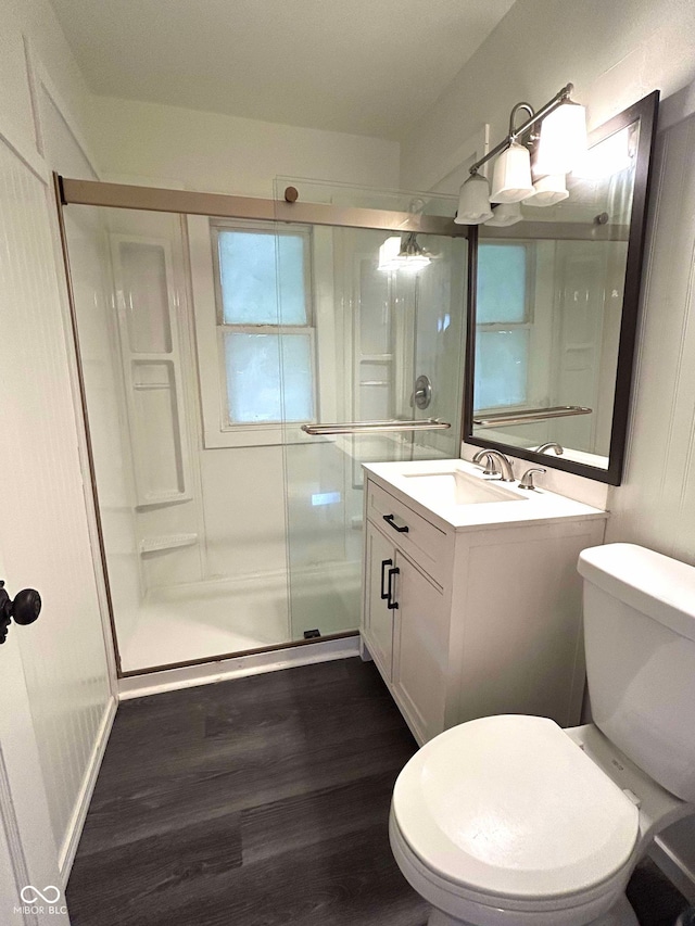 bathroom with toilet, walk in shower, vanity, and wood-type flooring