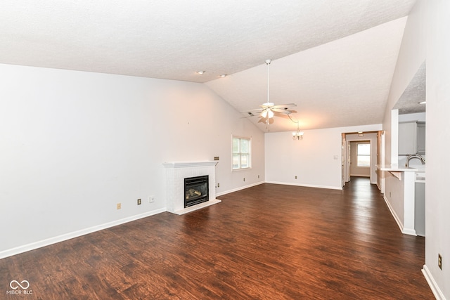 unfurnished living room featuring dark wood-type flooring, ceiling fan, lofted ceiling, and a fireplace