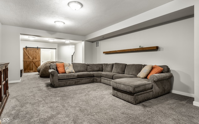 living room with a textured ceiling, a barn door, and carpet flooring