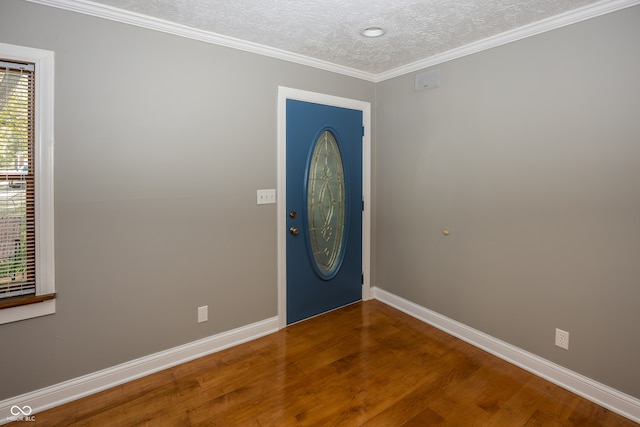 foyer with a wealth of natural light, hardwood / wood-style floors, crown molding, and a textured ceiling