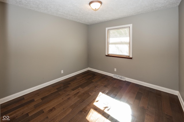 spare room with baseboards, visible vents, a textured ceiling, and dark wood-type flooring