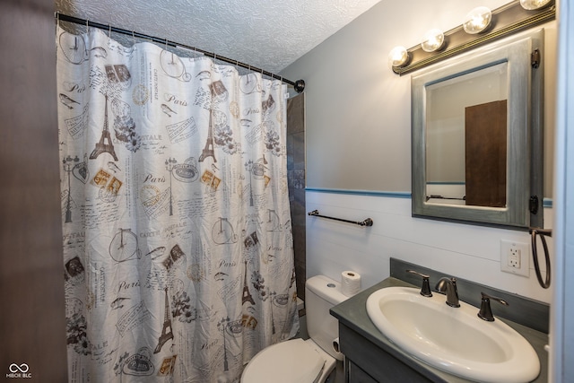 full bathroom featuring wainscoting, toilet, vanity, curtained shower, and a textured ceiling