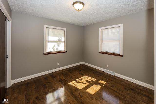 spare room with a textured ceiling, visible vents, and baseboards