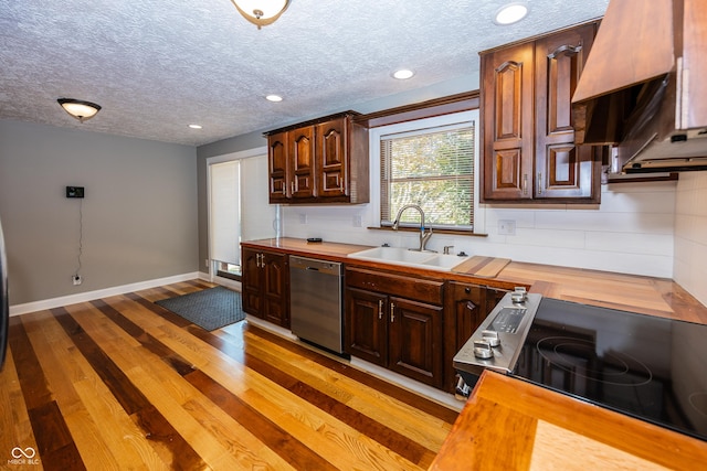 kitchen with a sink, wood counters, range, stainless steel dishwasher, and a textured ceiling