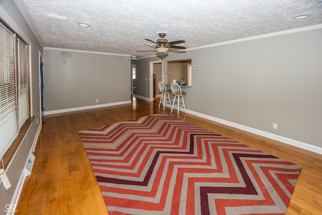 interior space featuring ornamental molding, hardwood / wood-style floors, a textured ceiling, and ceiling fan