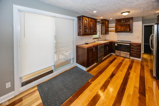 kitchen with a textured ceiling, a sink, dark brown cabinets, and appliances with stainless steel finishes