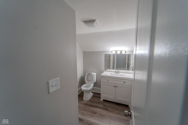 bathroom with vanity, hardwood / wood-style floors, vaulted ceiling, and toilet