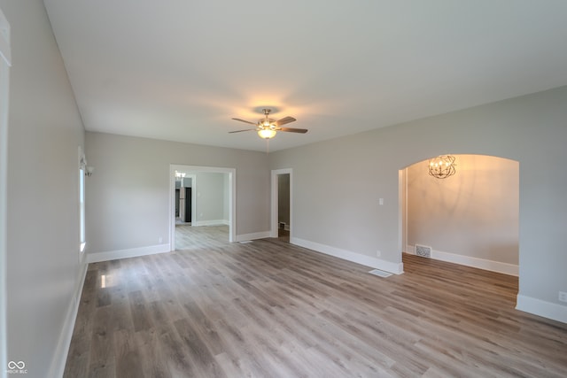 empty room featuring light hardwood / wood-style floors and ceiling fan with notable chandelier