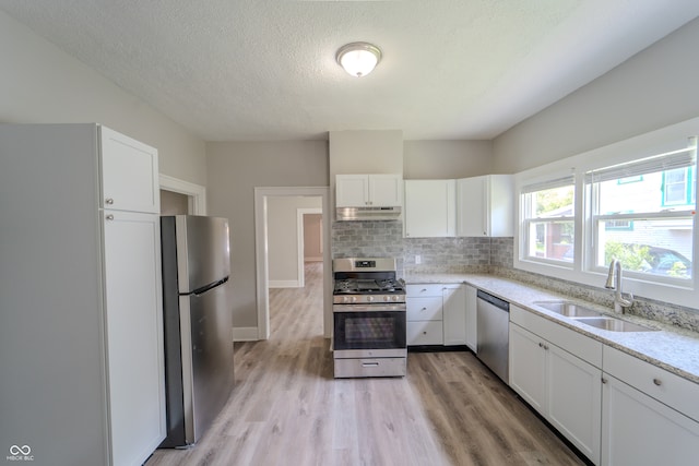 kitchen featuring decorative backsplash, sink, light wood-type flooring, white cabinetry, and appliances with stainless steel finishes