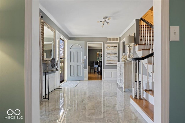 entrance foyer featuring stairs, visible vents, marble finish floor, and crown molding