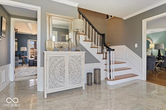 stairs featuring a wainscoted wall, marble finish floor, crown molding, and a decorative wall