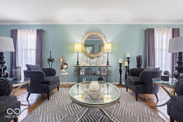 living area with wood finished floors, baseboards, and ornamental molding