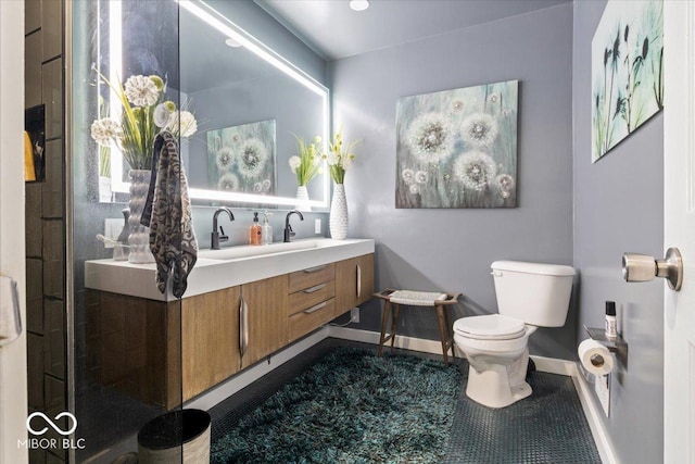 bathroom featuring vanity, toilet, baseboards, and a shower with door