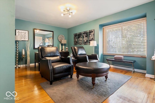 living area featuring baseboards, a notable chandelier, and hardwood / wood-style flooring