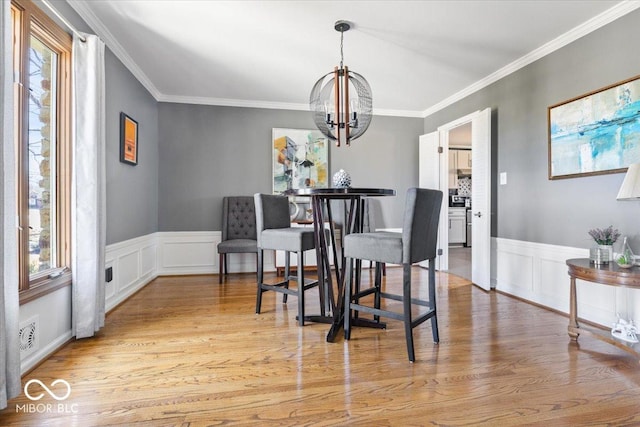 dining area featuring light wood-type flooring, a notable chandelier, and crown molding