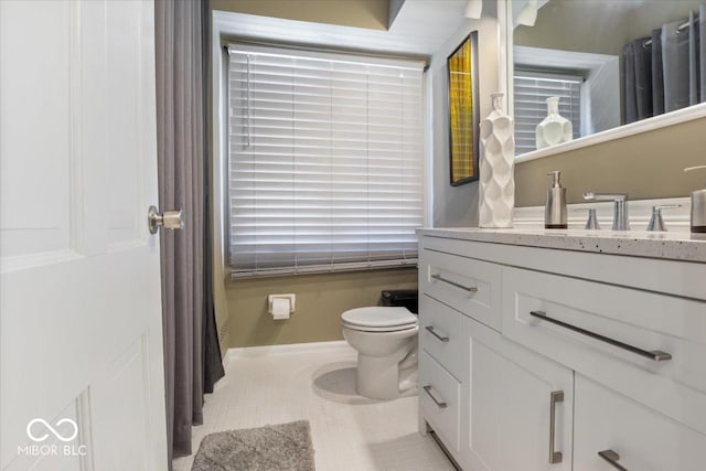 bathroom with toilet, vanity, and tile patterned flooring