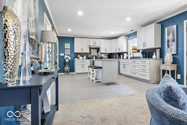 kitchen featuring a breakfast bar area, a kitchen island, white cabinetry, crown molding, and backsplash