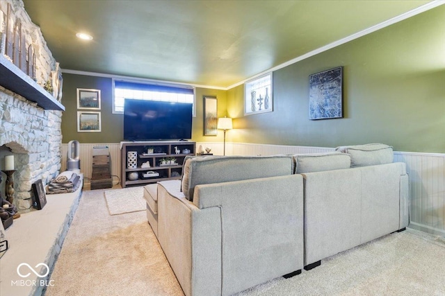 living area featuring crown molding, carpet flooring, a fireplace, and wainscoting