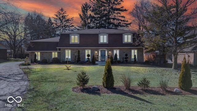 view of front of house featuring brick siding, a lawn, and roof with shingles