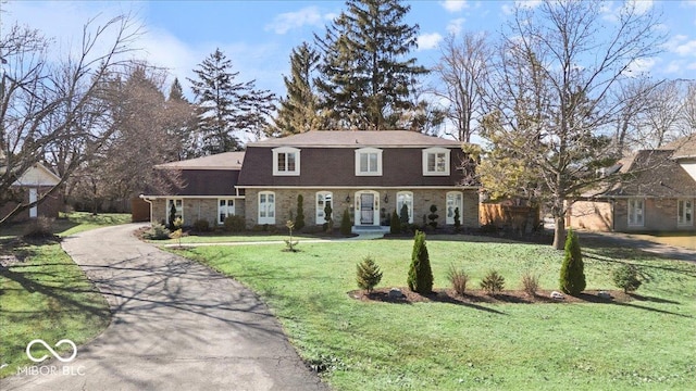 view of front of house featuring driveway, brick siding, and a front yard