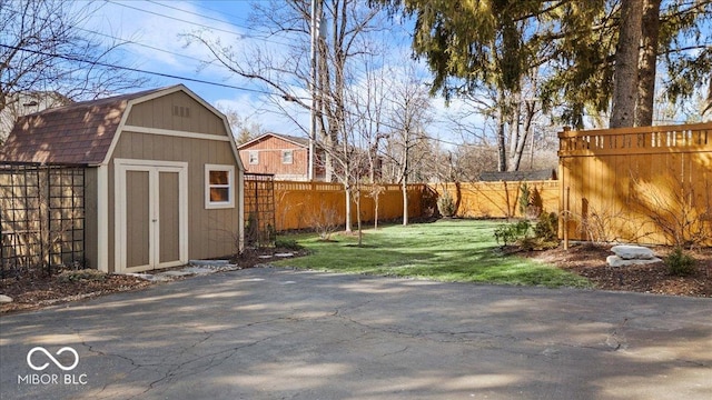 view of yard featuring an outbuilding, a fenced backyard, and a shed