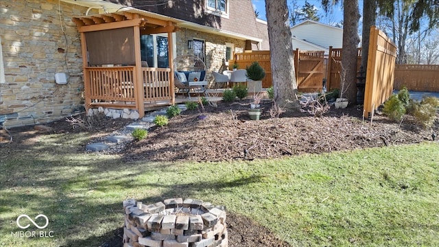 view of yard with a wooden deck, a fire pit, and fence